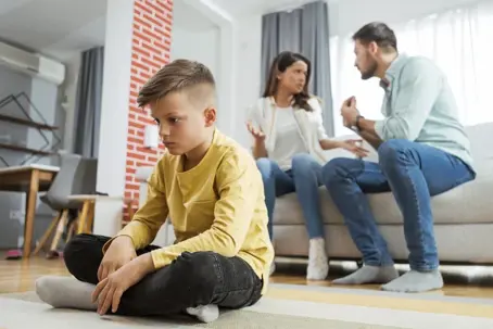 sad child with parents fighting in the background